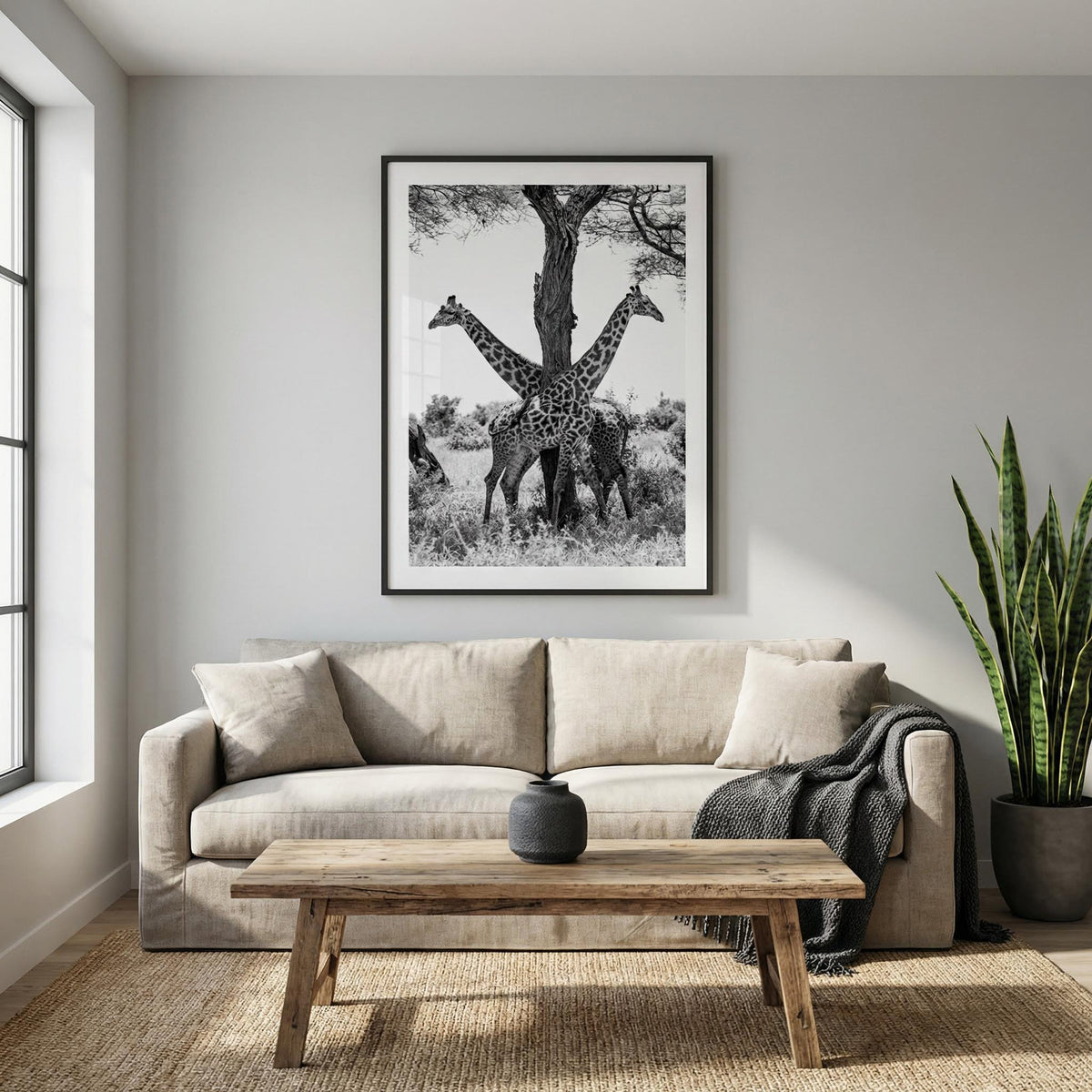 Giraffe Black And White Art Print hanging above a sofa with beige cushions and a wooden table in a living room