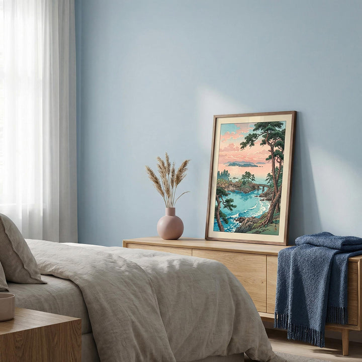 Print leaning on a bedroom dresser of a Japanese coastal village with pink sky and blue sea