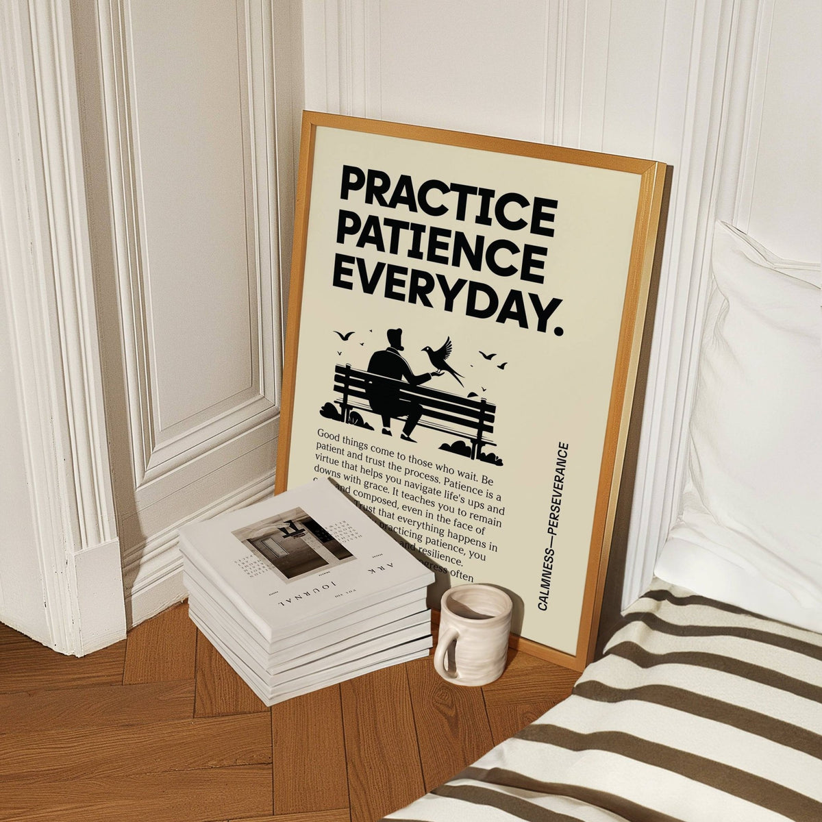 Print leaning on floor with person feeding bird artwork and black text beside a ceramic mug and magazines