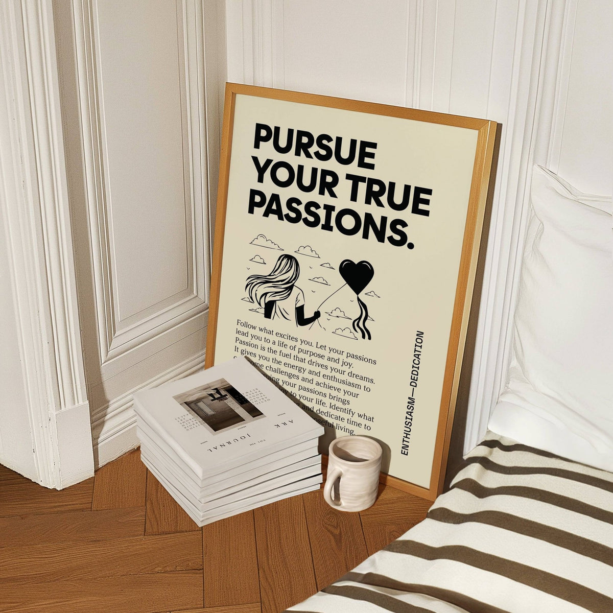 Inspirational wall art leaning on floor with text and illustration beside ceramic mug and stack of books