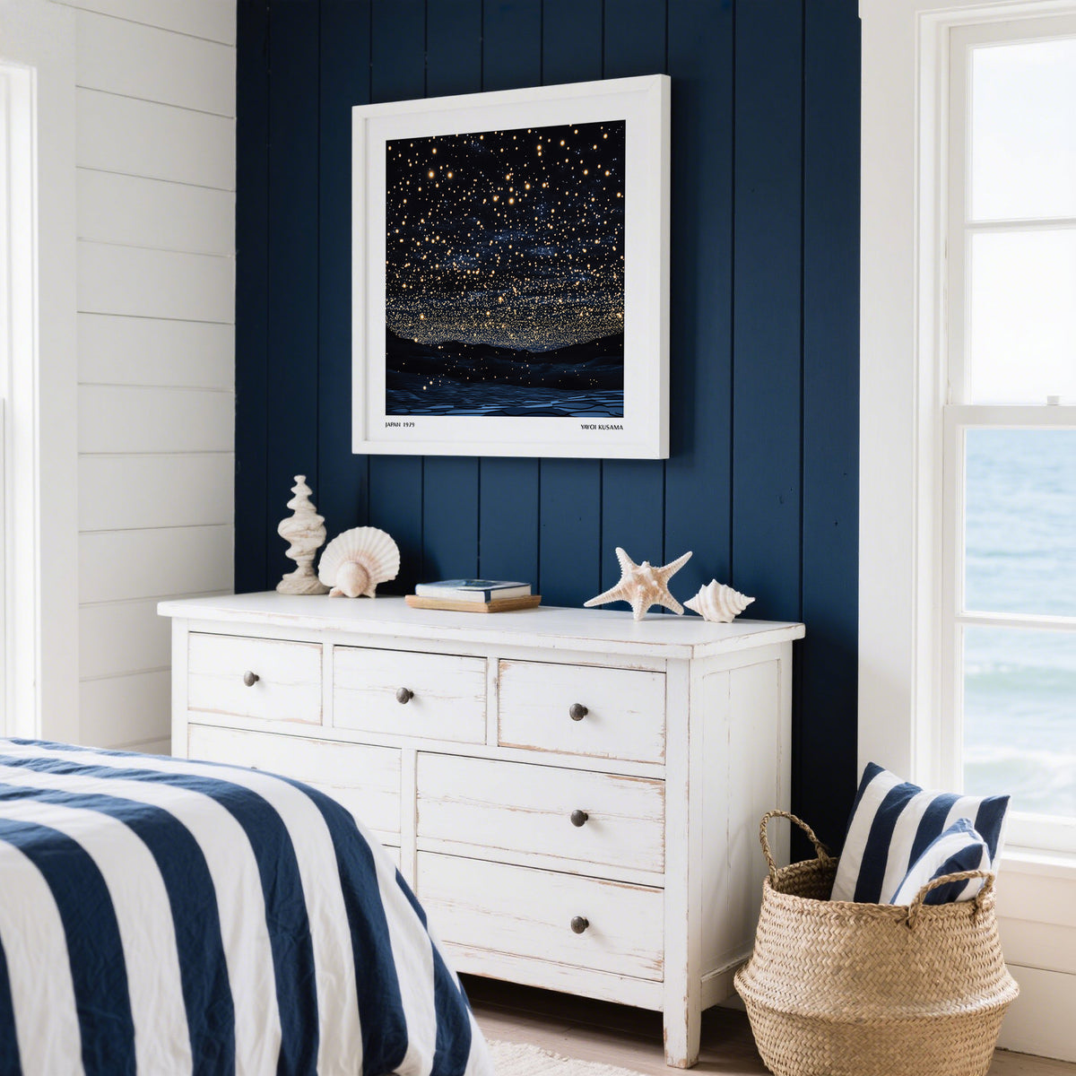 Starry Night Print framed on a dark blue wall above a white chest with seashell decorations in a coastal bedroom