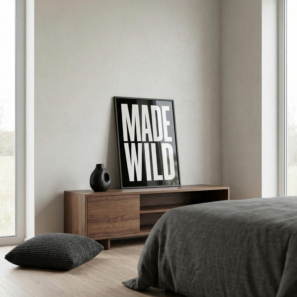 Made Wild art print leaning on a wooden sideboard with a small black vase in a bedroom