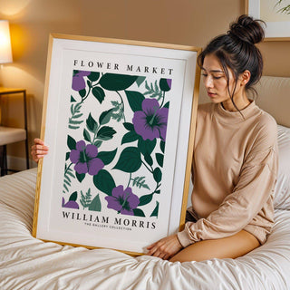 Framed Purple Flower Artwork with purple flowers and green leaves held by woman on bed