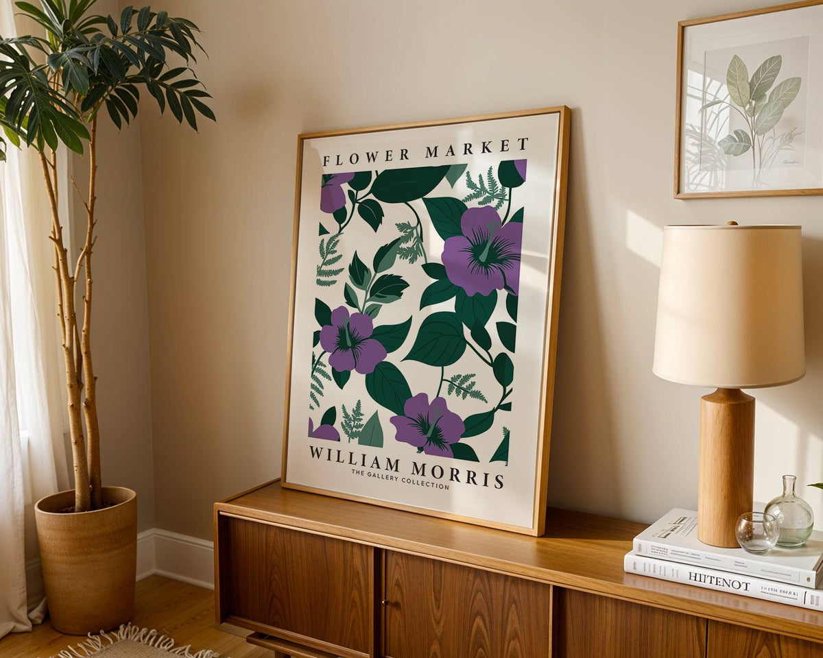 Purple flower artwork print leaning on a wooden cabinet next to a lamp and plant