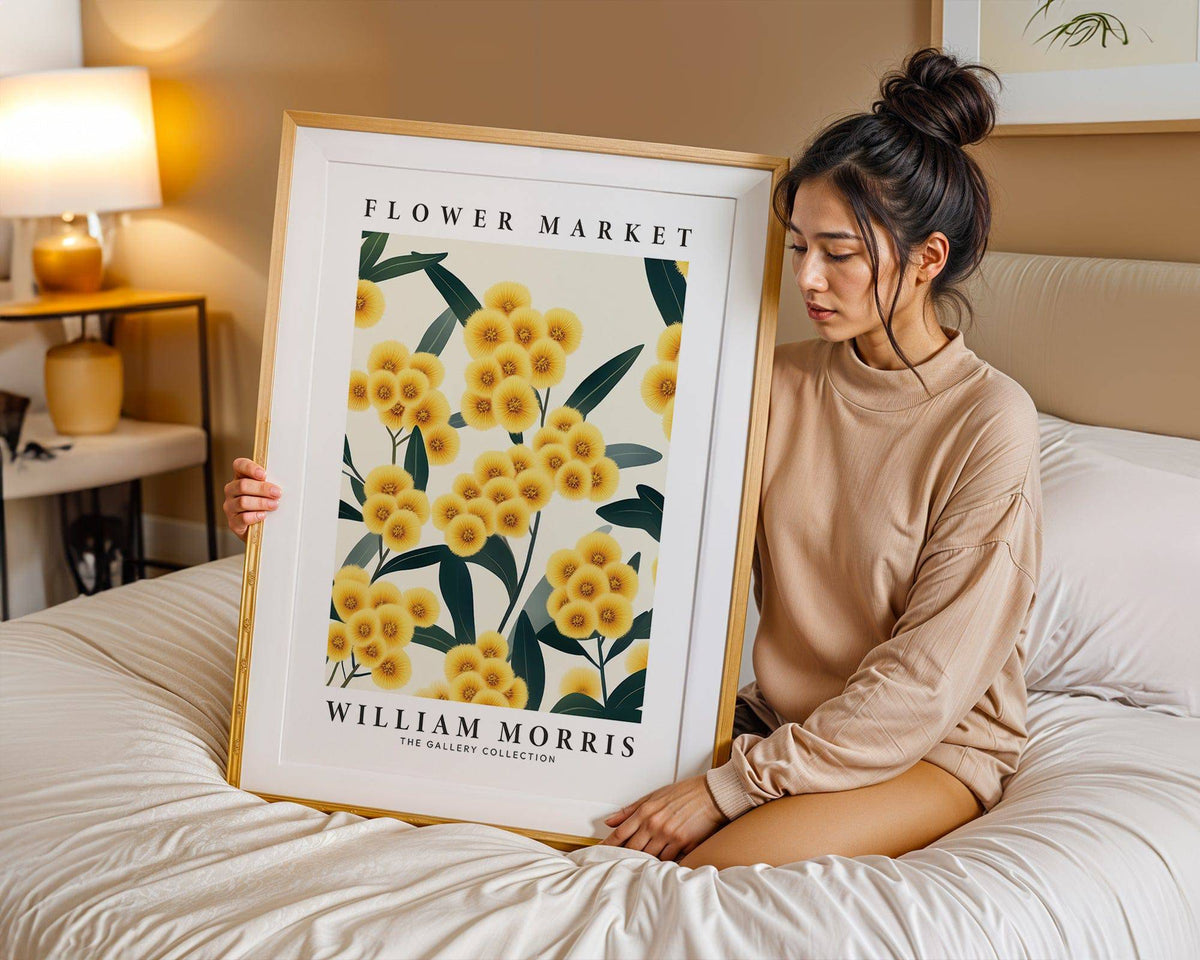 Framed Yellow Flower Wall Art held by a woman sitting on a bed with beige bedding