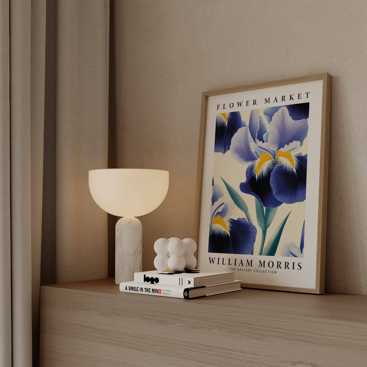 Print leaning on a shelf featuring a blue iris flower with yellow accents next to a modern lamp and books