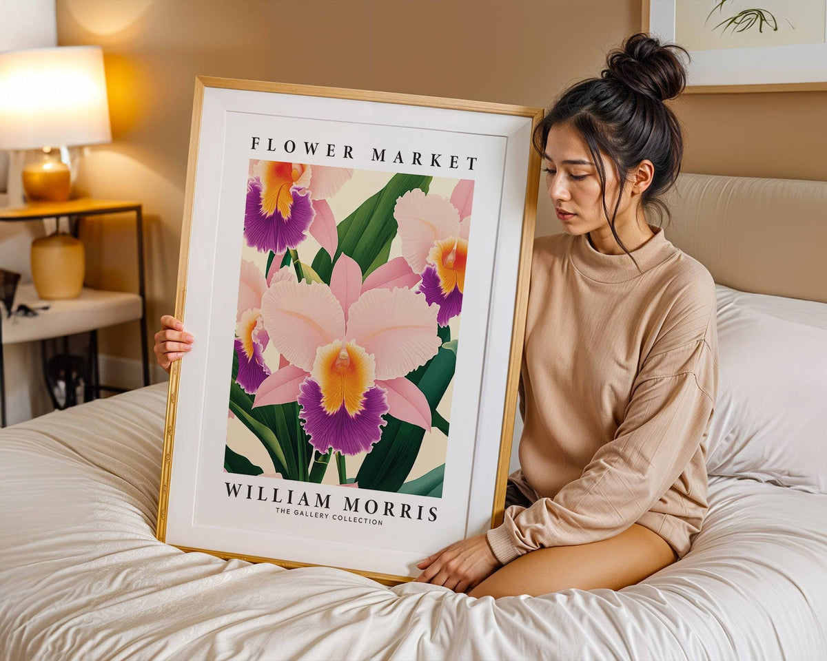 Framed print of a pink orchid flower illustration held by a woman sitting on a bed