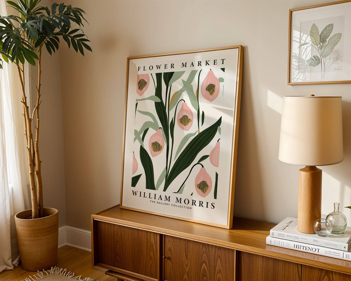 Paintings of Orchids leaning on a wooden cabinet with a table lamp and plant beside it