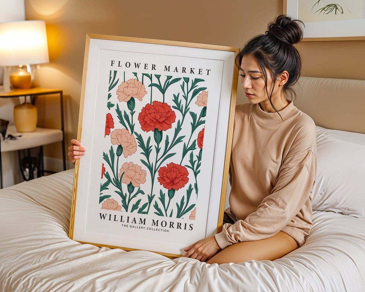 Framed print close-up of carnation flowers in red and peach with green leaves held on a bed