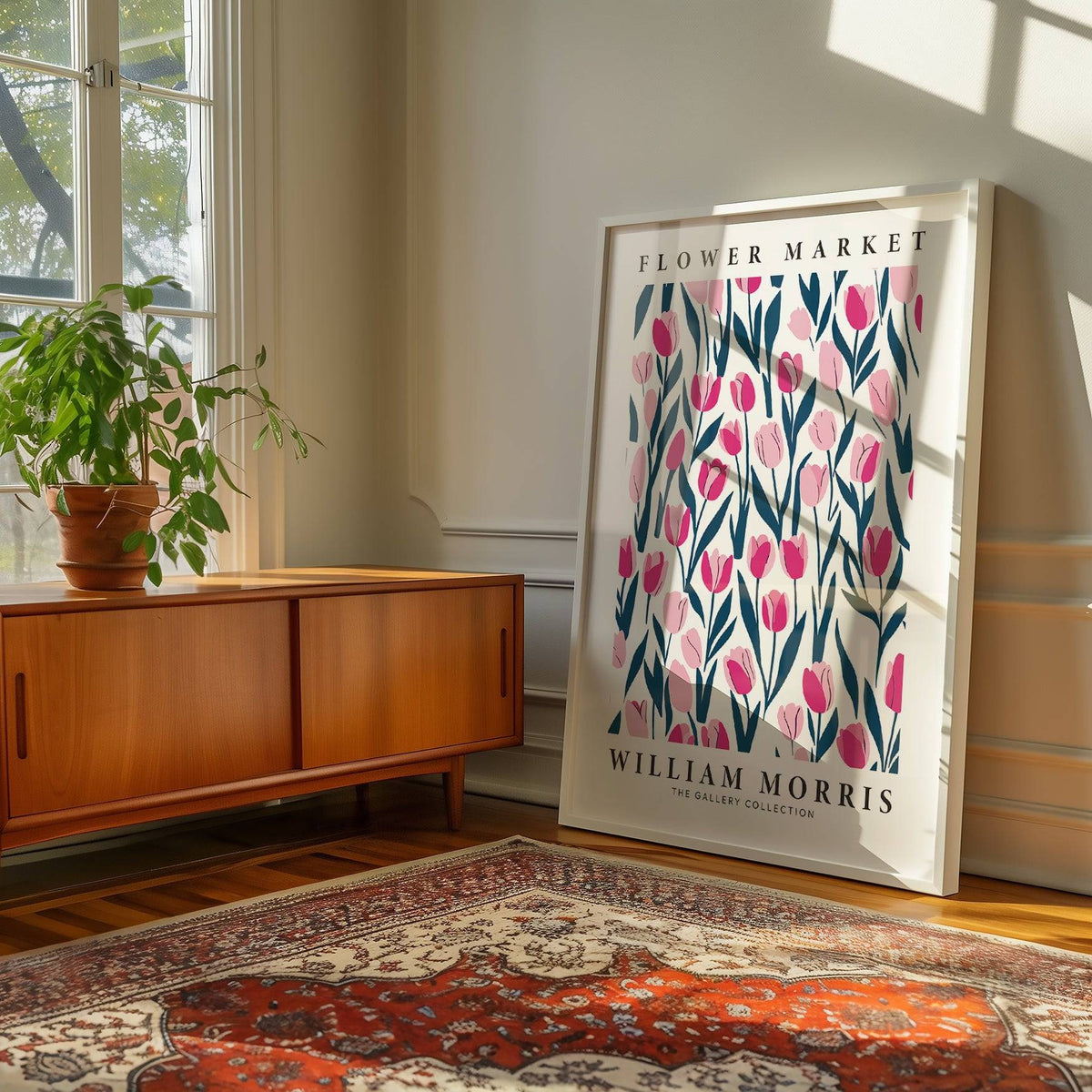 Print leaning on floor of tulip decor with pink flowers and dark green leaves by sideboard and plant
