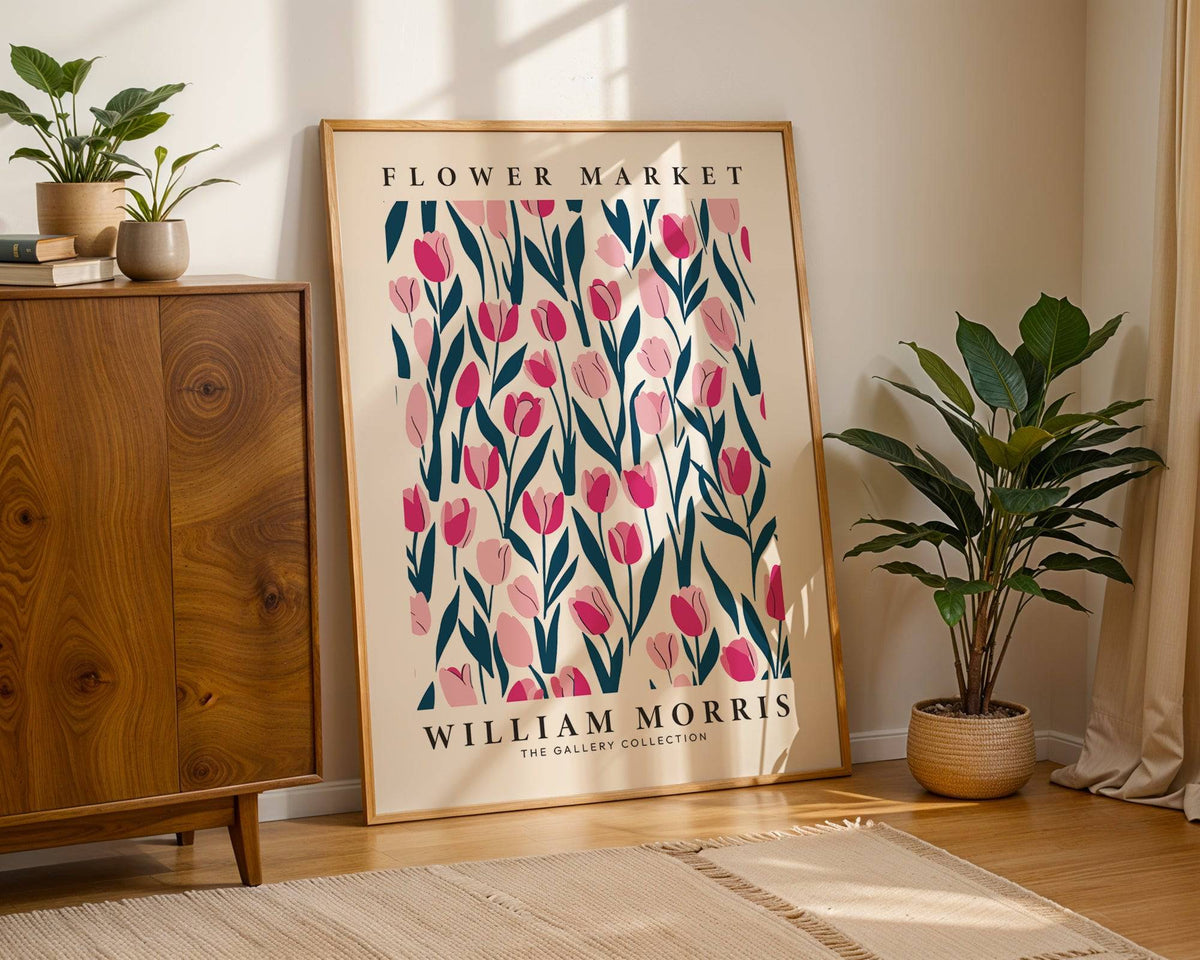 Print leaning on floor of pink tulips with blue leaves and wooden sideboard nearby