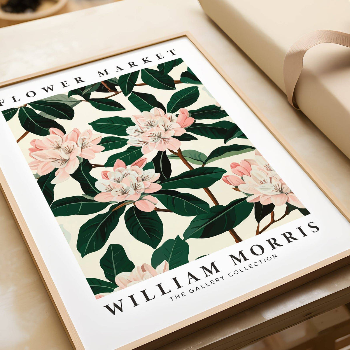 Close-up of Magnolia wall art showing pink flowers and dark green leaves in a wooden frame beside gift wrap