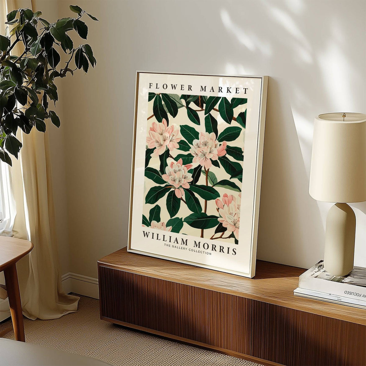 Magnolia wall art leaning on wooden cabinet with a lamp and books beside it