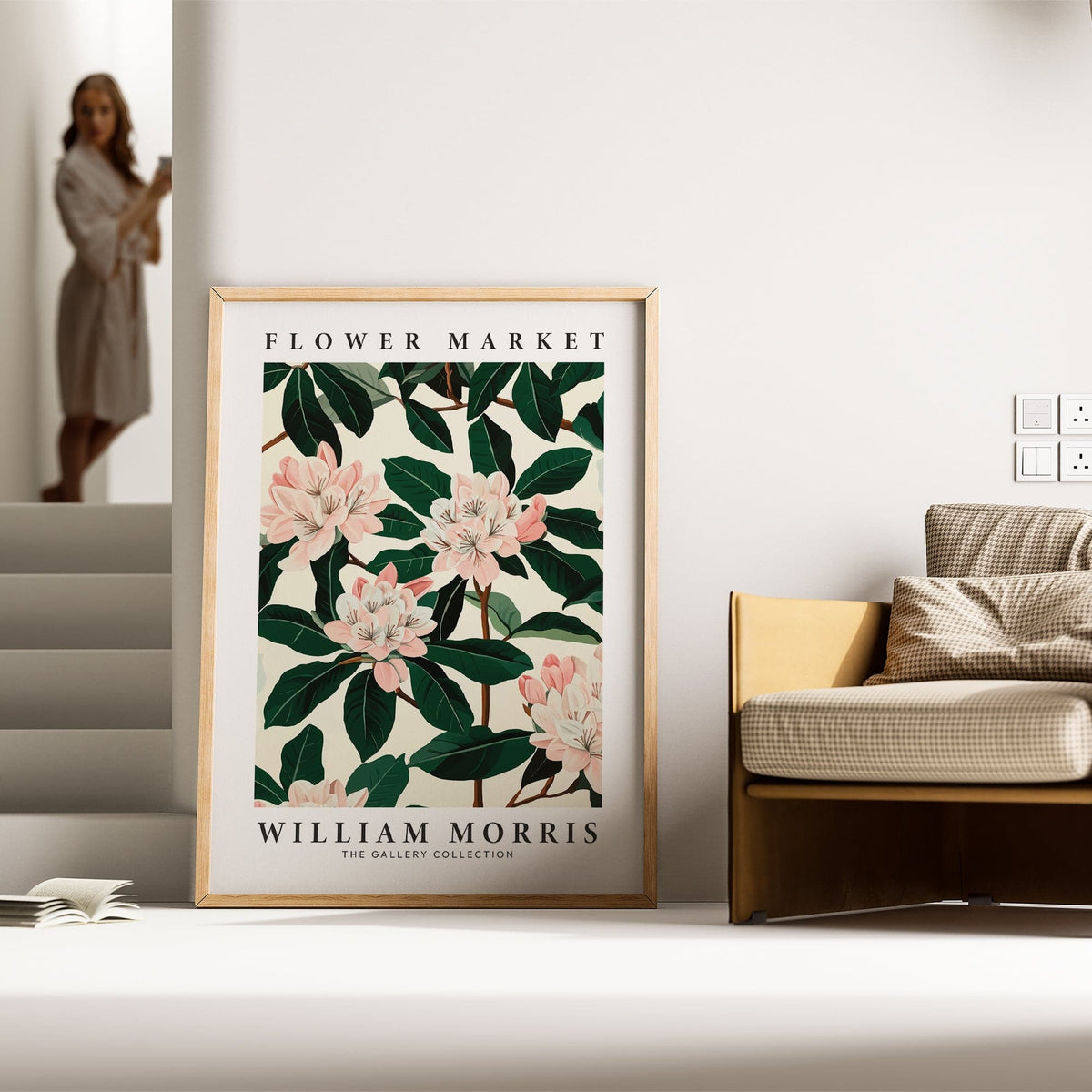 Magnolia wall art with pink flowers and green leaves leaning against a wall near a beige sofa