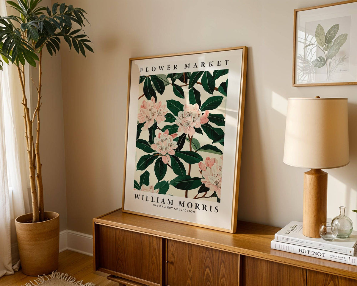 Magnolia wall art leaning on a wooden sideboard with a lamp and plant in natural tones