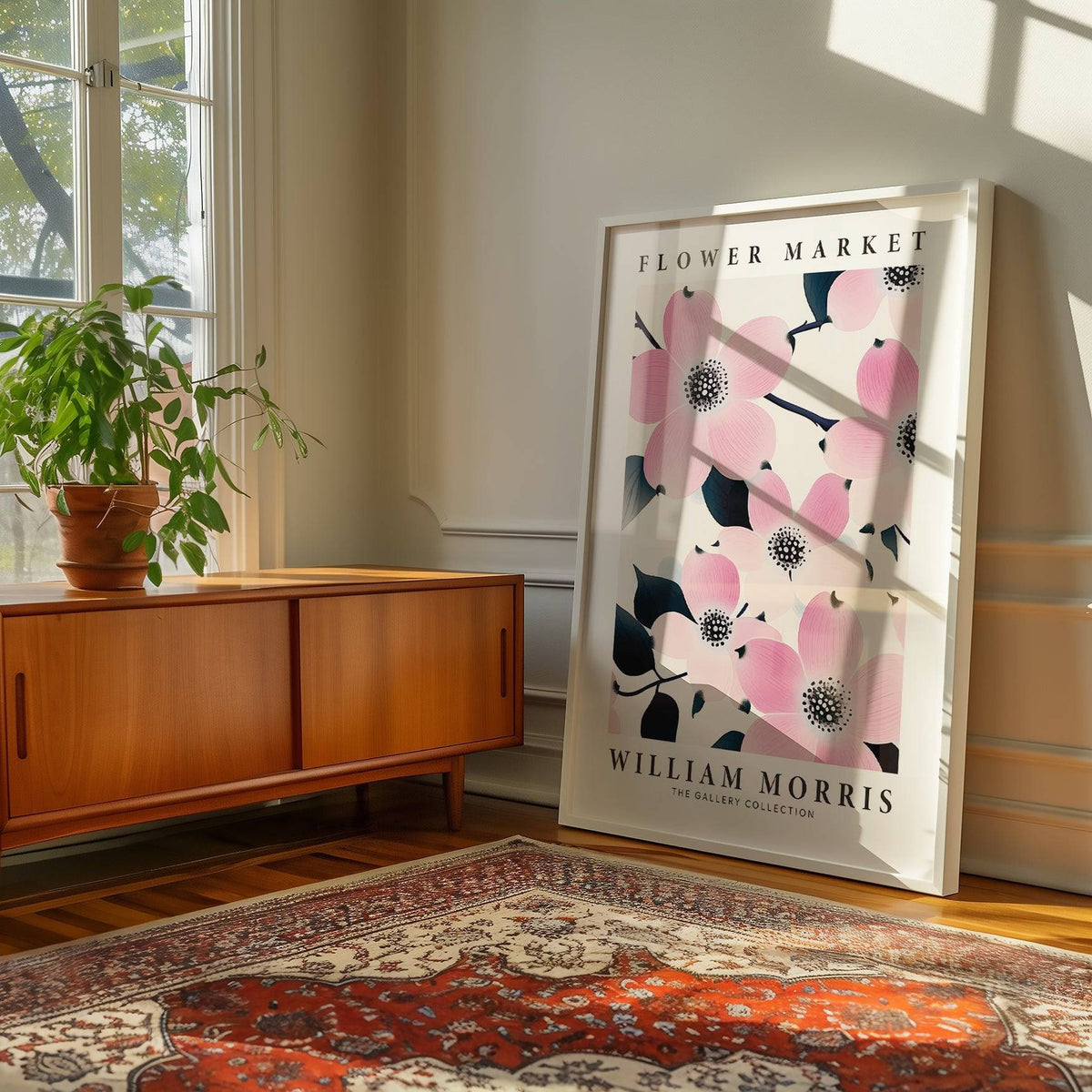 Print leaning on the floor with pink dogwood flowers and blue leaves near a wooden cabinet and a green plant