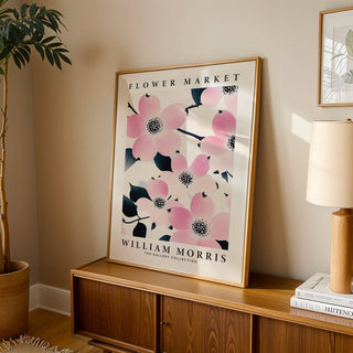 Prints for Bathroom leaning print of pink dogwood flowers with dark leaves on a wooden sideboard with a lamp and a plant