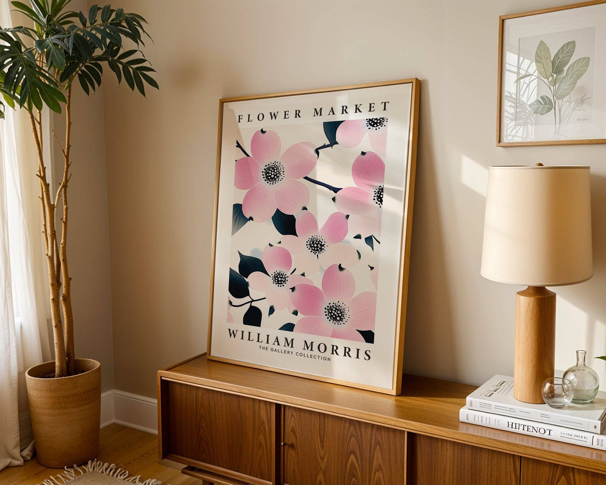 Prints for Bathroom leaning print of pink dogwood flowers with dark leaves on a wooden sideboard with a lamp and a plant