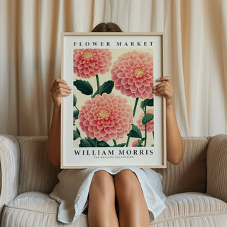 Pink wall decor showing a pink dahlia flower botanical illustration held by a person on a beige sofa