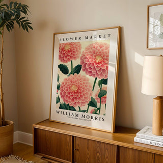 Pink wall decor leaning on a wooden sideboard with beige lamp and plant in neutral room