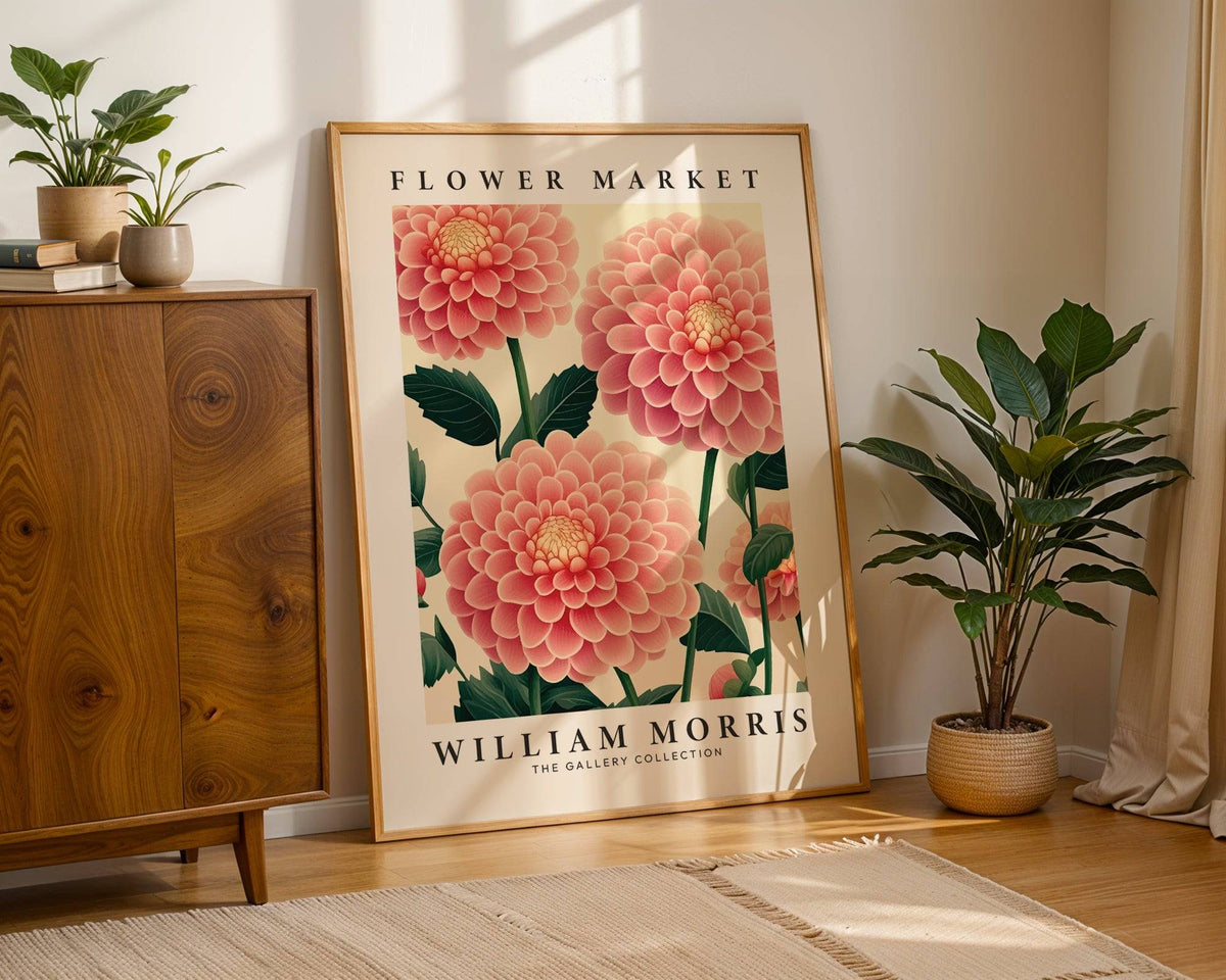 Print leaning on wooden floor with pink dahlia flowers and green leaves beside a green plant