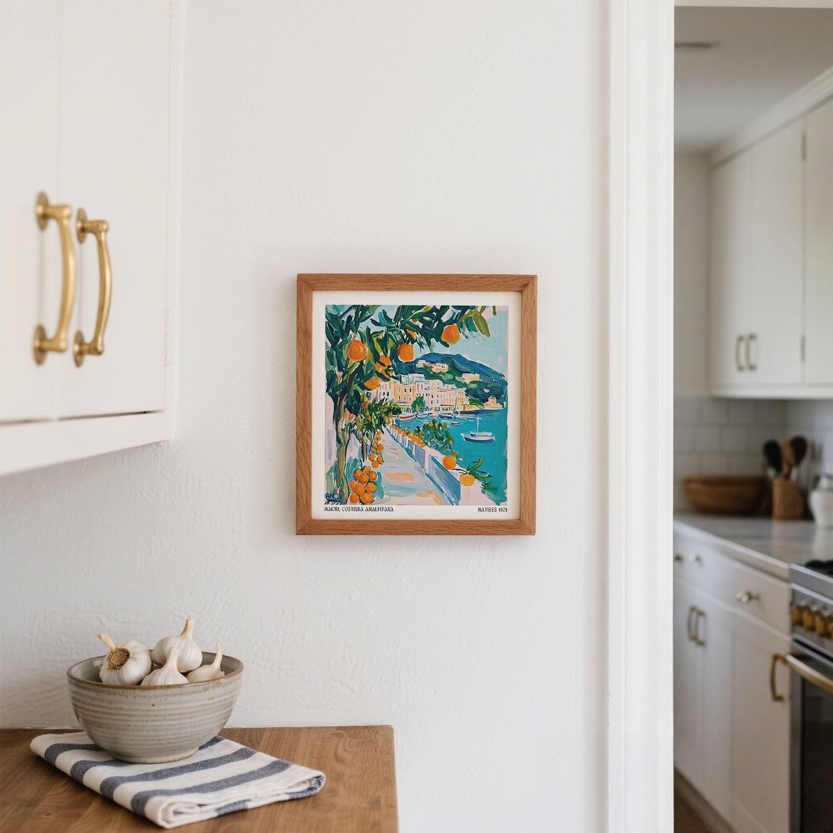 Art Prints of Italy framed print of an orange tree by a seaside path in a white kitchen above a wooden countertop