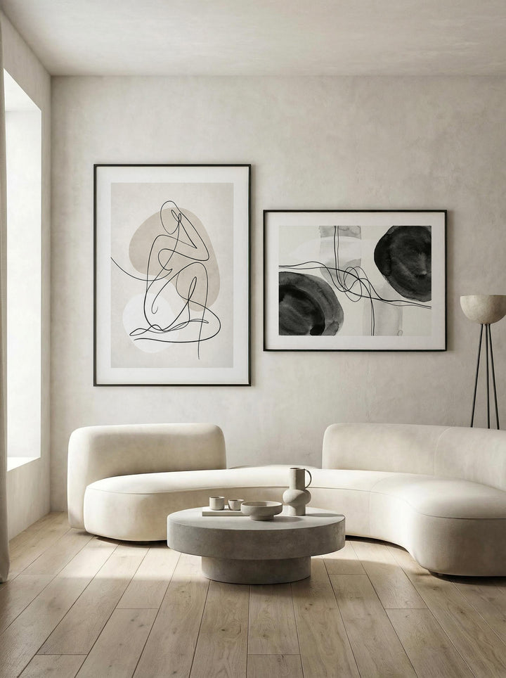 Print on a wall in a living room of abstract line art duo with black and beige shapes and a curved cream sofa