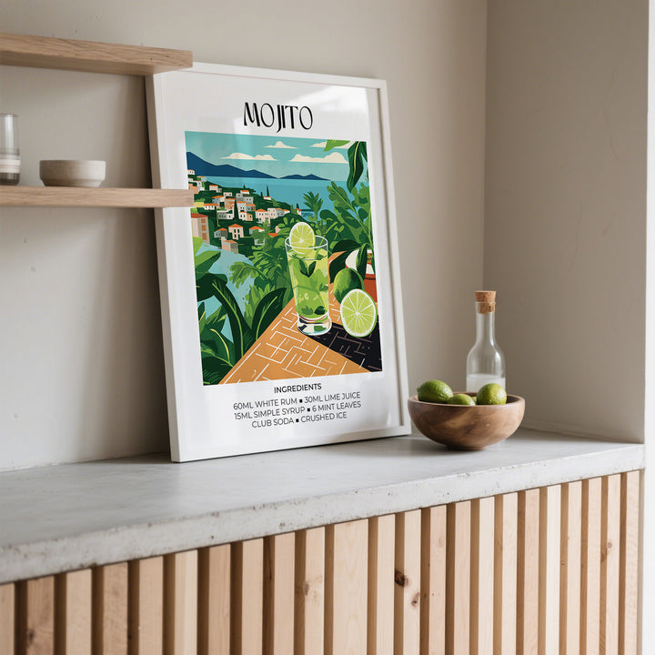 Print of a mojito cocktail with lime and mint leaves leaning on a shelf with a wooden bowl of limes