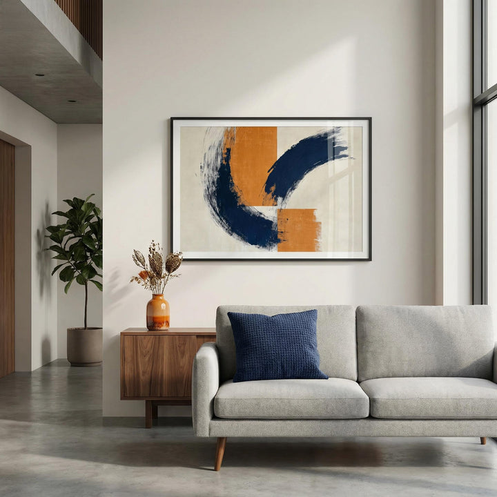 Framed blue orange wall poster with abstract brush strokes above a wooden sideboard with a vase