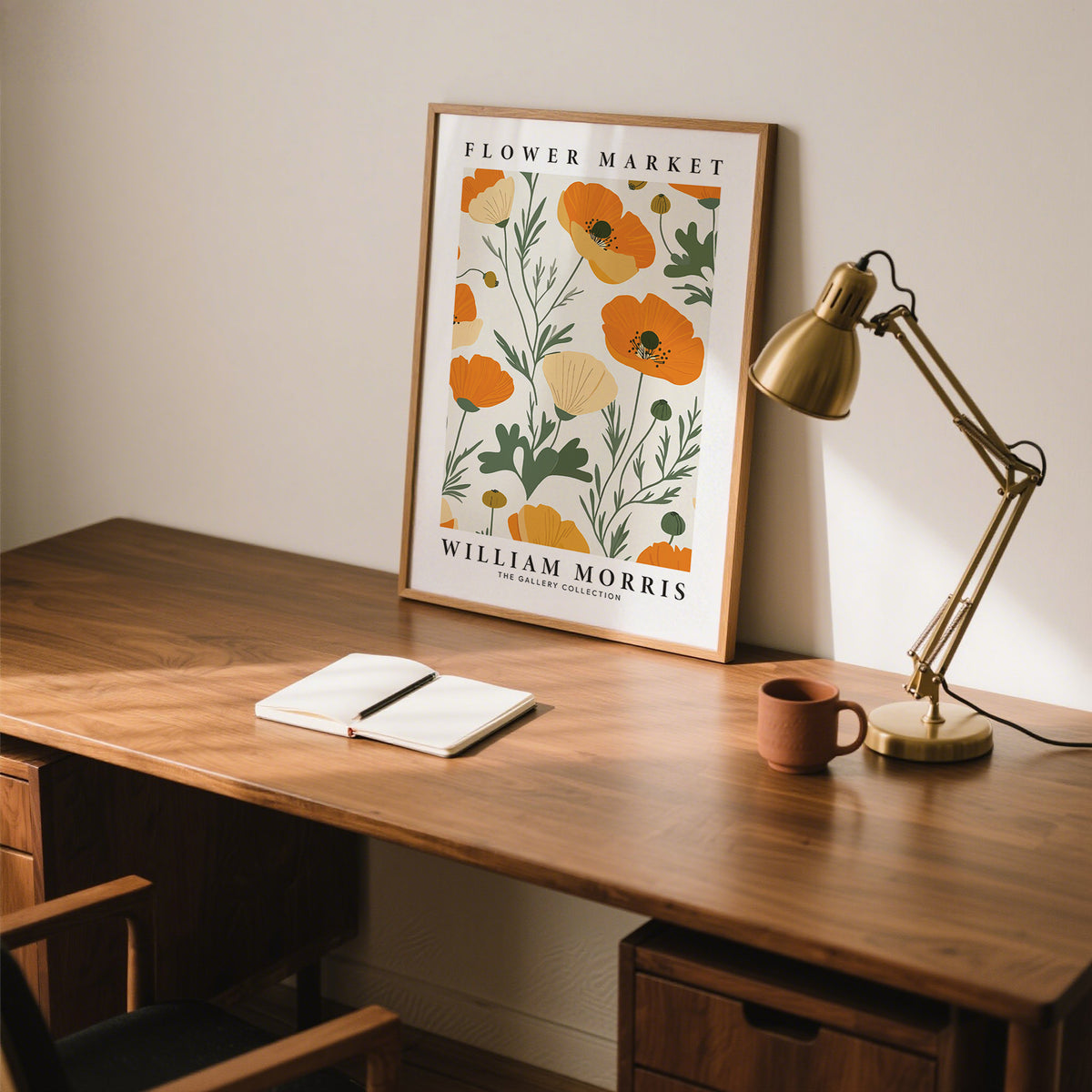 Print leaning on a wooden desk featuring orange poppy flowers and green stems with a brass desk lamp
