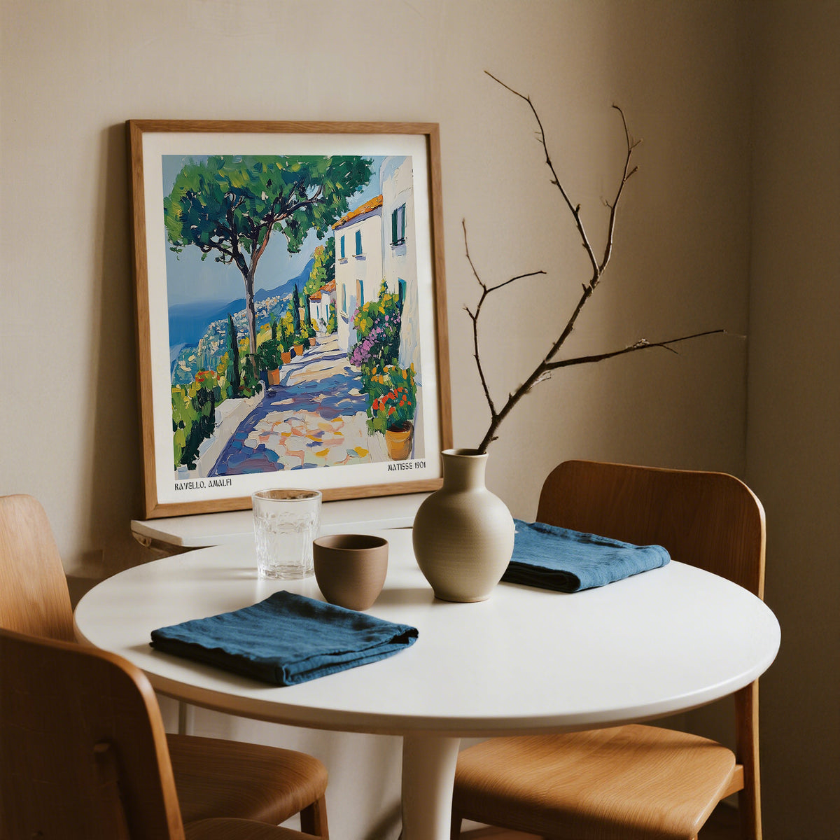 Prints of Amalfi Coast wall art of a Mediterranean path with trees and houses leaning on a table in a dining area