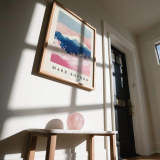 Framed Mount Fuji Art with snow-capped mountain in pink and blue above a wooden bench with a pink sphere