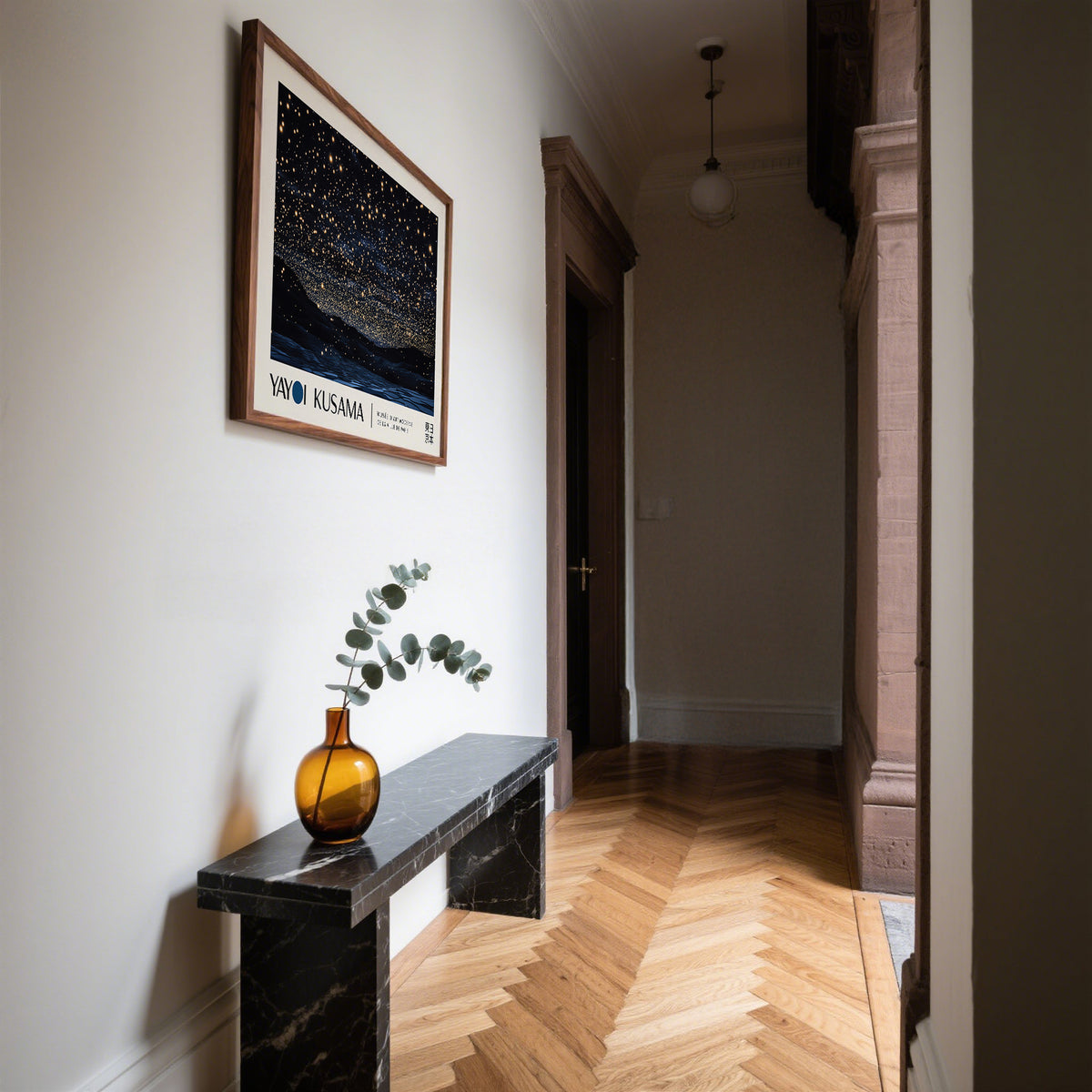 Night Sky Art framed print of a starry night sky with gold and black tones above a bench with a brown vase in a hallway