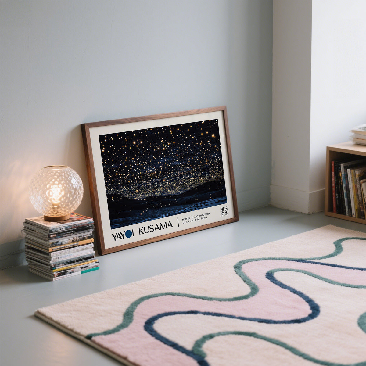 Print of night sky art with golden stars leaning on a floor beside a glowing lamp