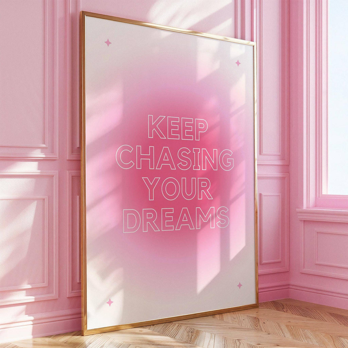 Framed print of Keep Chasing Your Dreams in pink and white leaning against a pink wall