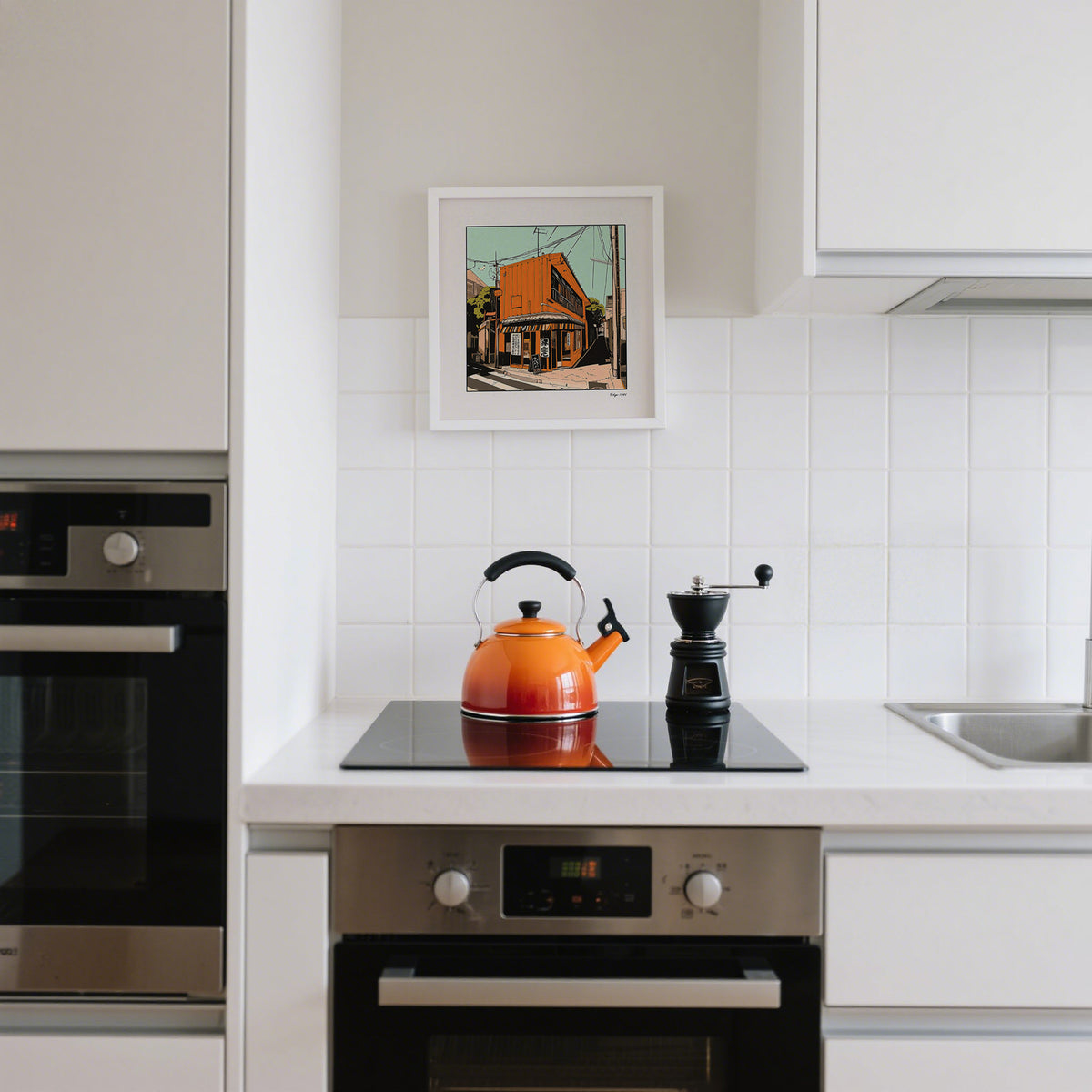 Tokyo wall art print of an orange street building hung above a stove with an orange kettle in a kitchen