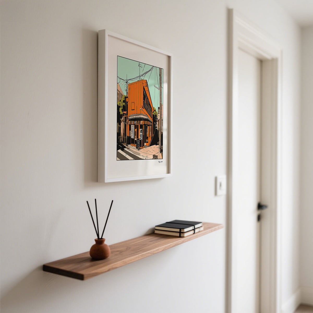 Tokyo wall art framed print of an orange street building above a wood shelf with a jar and books
