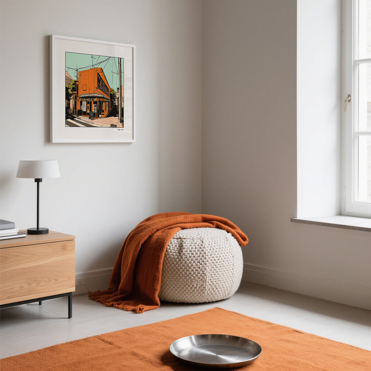 Tokyo wall art framed print showing an orange street building with a green sky in a minimalist room with an orange pouf