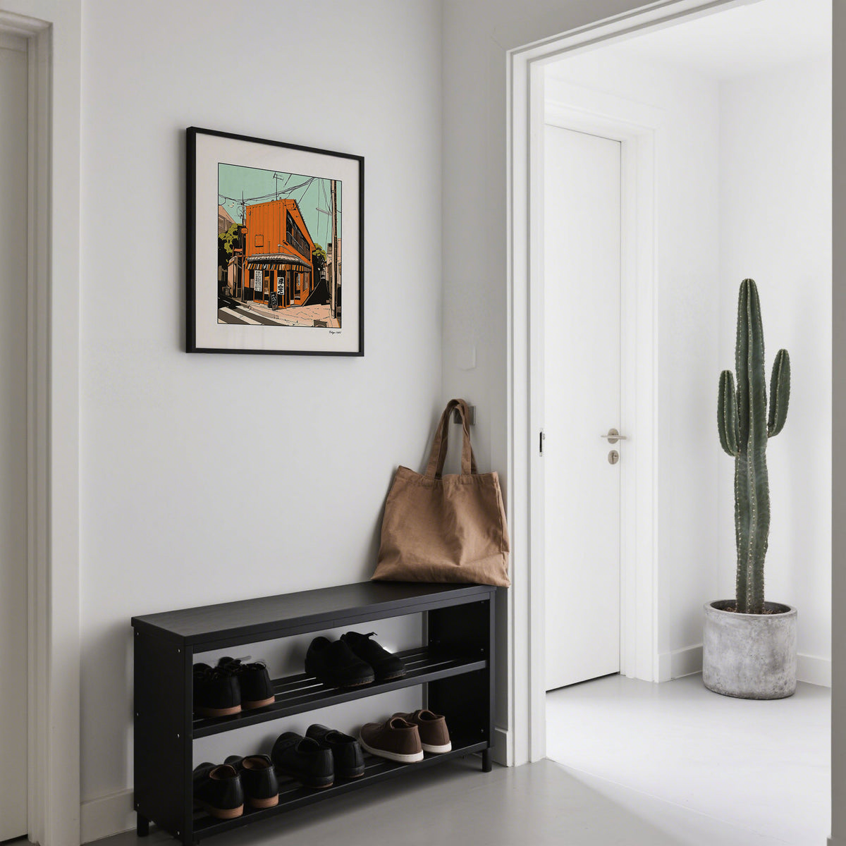 Tokyo wall art framed print with an orange street building above a shoe rack in a hallway