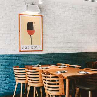 Modern Wine Wall Art print of a red wine glass in a wooden frame above a wooden table and chairs