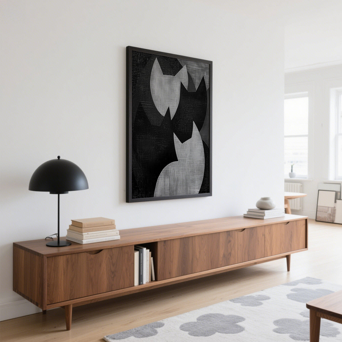 Big Cat Art print in black and grey abstract cat shapes above a wooden sideboard with a black lamp