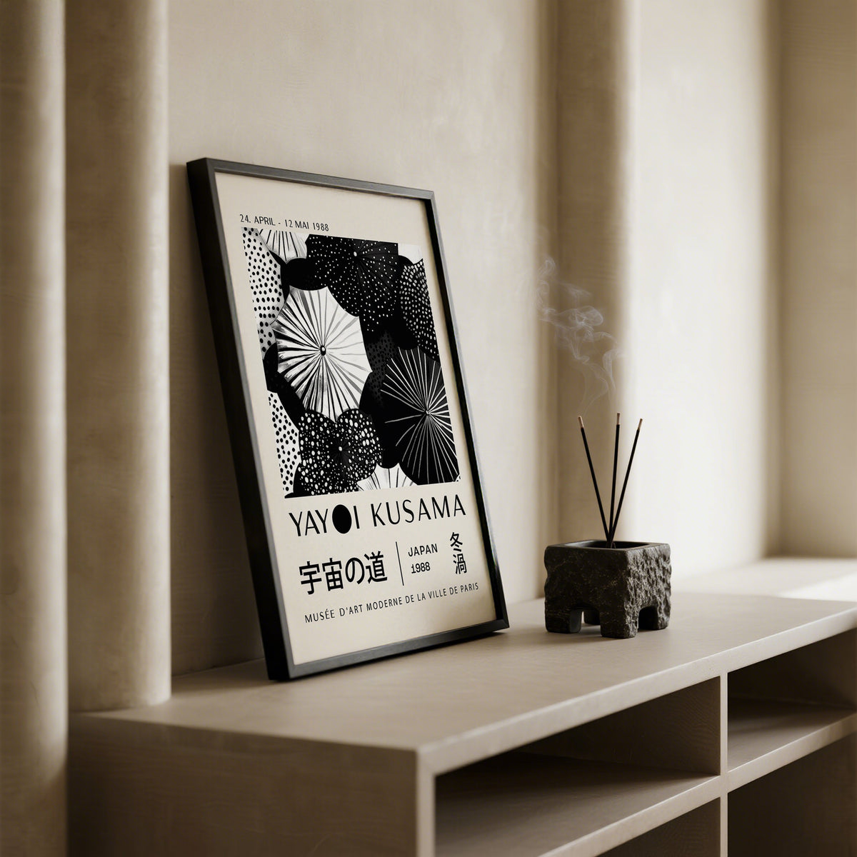 Print leaning on a shelf abstract black and white dots with a small incense holder nearby