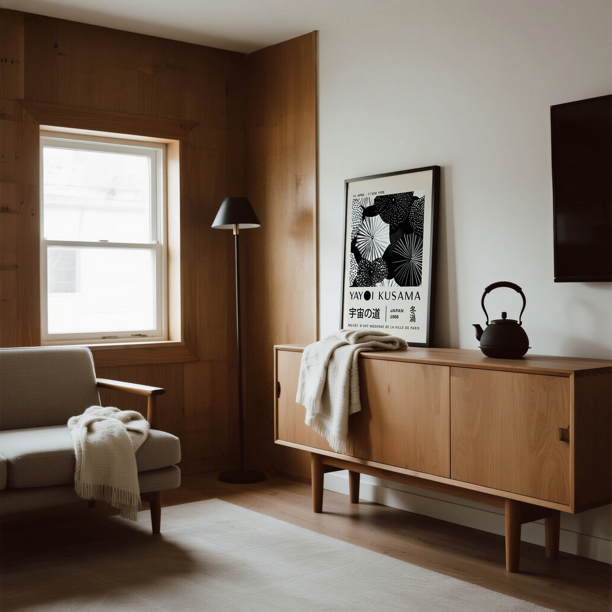 Winter wall art leaning on wooden sideboard with black teapot and cream throw in living room