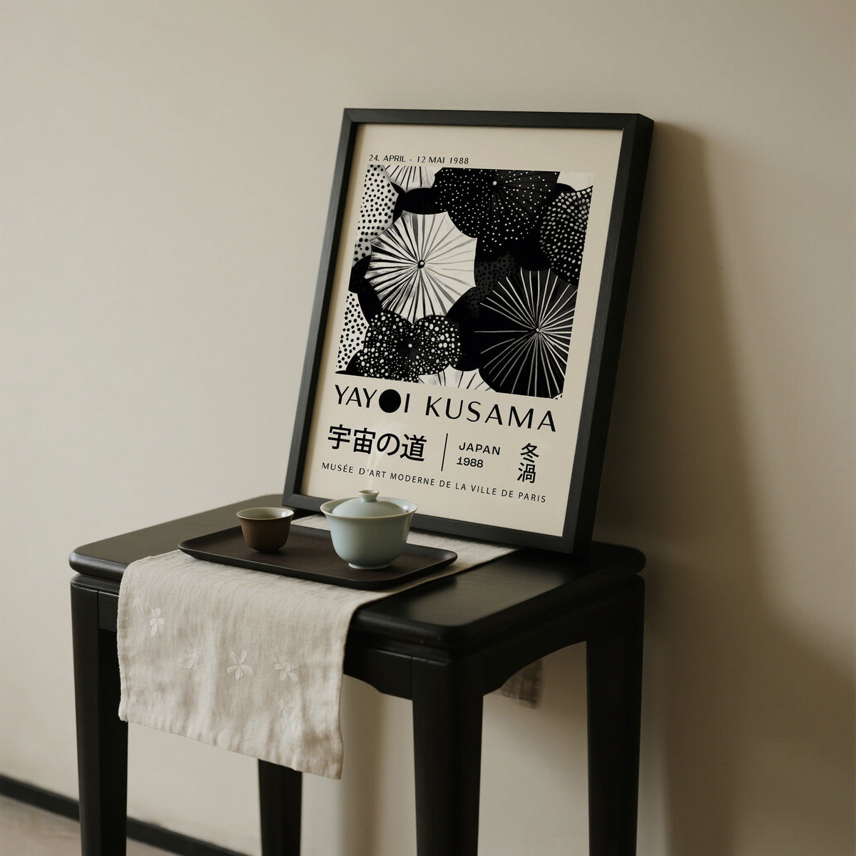Framed Winter Wall Art with black and white abstract dots leaning on a dark wooden table with teacups