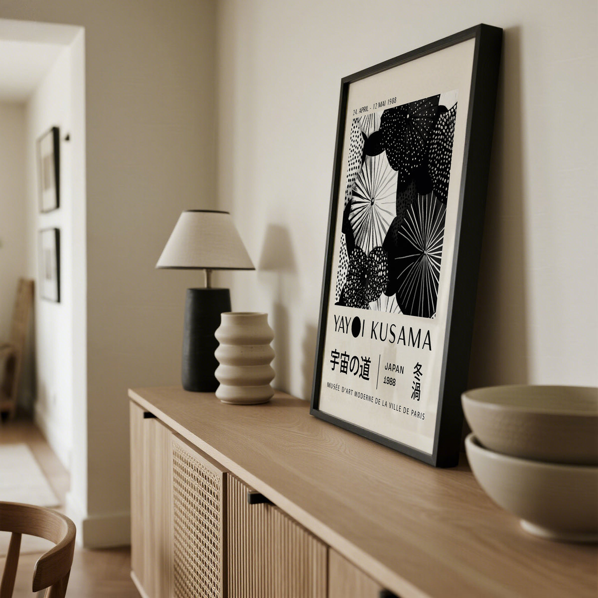 Winter wall art leaning on sideboard with black frame and black and white abstract dots in a beige room