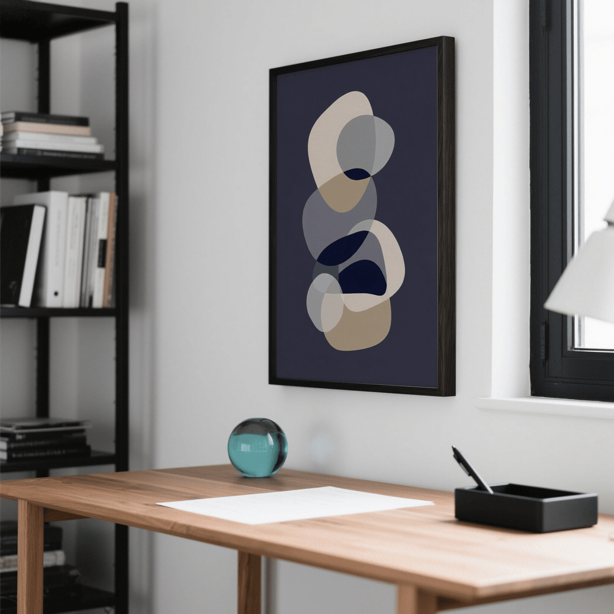 Abstract Modern Art framed print with overlapping beige and grey shapes above a wooden desk with a glass orb