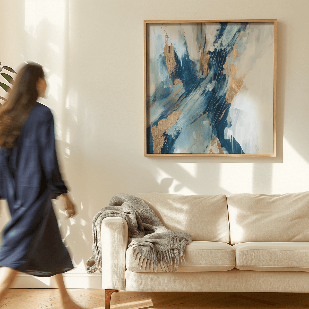 Blue abstract wall art with gold splashes above a cream sofa with a grey throw