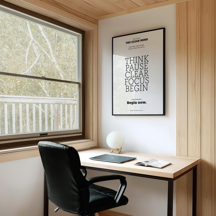 Motivational Art for the Office minimalist typographic print in a black frame above a desk with a black leather chair and a window