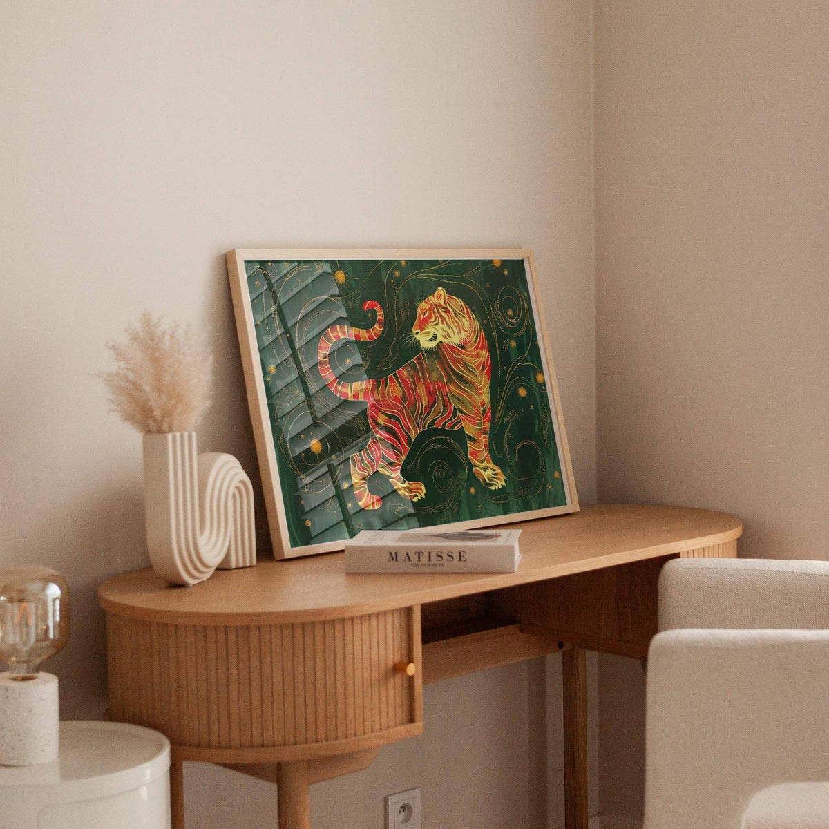 Print leaning on a shelf of a golden tiger illustration in red and gold with dark green background with a vase beside it