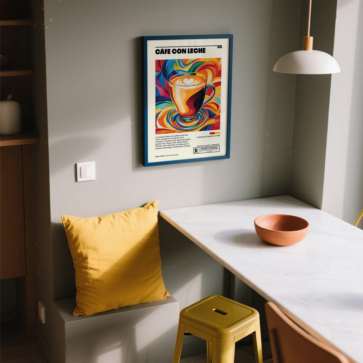 Framed Cafe Con Leche Art print with vibrant colours above a yellow cushion in a kitchen nook